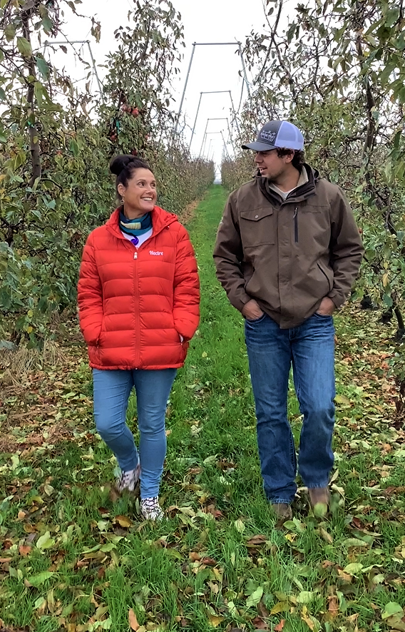 two people walking in orchard